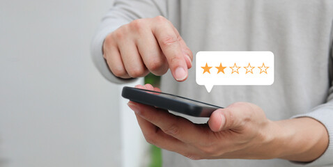close up on customer man hand use smartphone and pressing two star (poor rating) feedback rank for...
