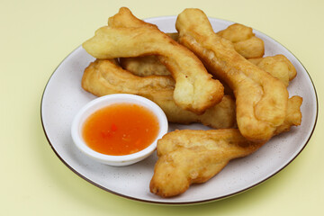 Cakwe or Youtio, popular Southeast and East Asian cuisine, made from Chinese dough and deep fry, savory taste served with chili sauce. Isolated background with copy space.