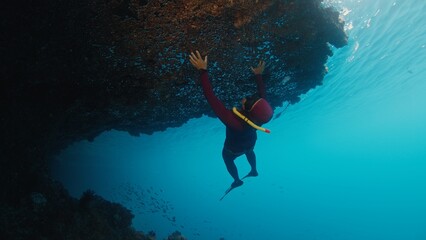 Naklejka premium Man freedives underwater in the tropical sea in Raja Ampat in Indonesia
