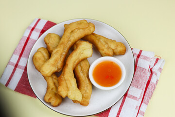 Cakwe or Youtio, popular Southeast and East Asian cuisine, made from Chinese dough and deep fry, savory taste served with chili sauce. Isolated background with copy space.