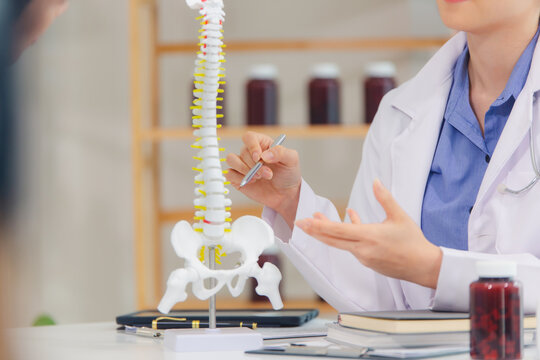 An orthopedic doctor shows a spinal model to a patient in a human spinal hospital. Diseases and disorders of the spinal cord, back pain, lumbar pain, orthopedic surgery, chiropractic, office syndrome