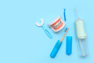 Jaw model with oral irrigator and toothbrushes on blue background