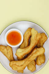 Cakwe or Youtio, popular Southeast and East Asian cuisine, made from Chinese dough and deep fry, savory taste served with chili sauce. Isolated background with copy space.