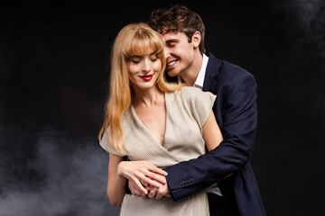Elegant couple embracing smiling on black background with smoke