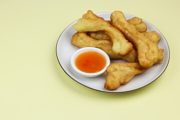 Cakwe or Youtio, popular Southeast and East Asian cuisine, made from Chinese dough and deep fry, savory taste served with chili sauce. Isolated background with copy space.