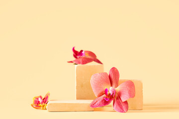 Decorative podiums with beautiful orchid flowers on yellow background