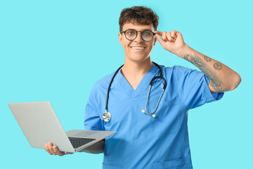 Male medical student with modern laptop on blue background