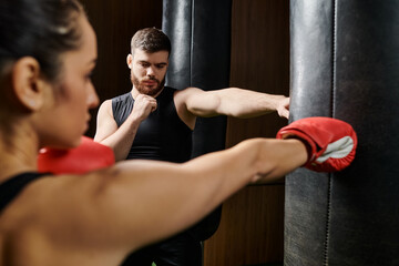 A male trainer coaches a brunette sportswoman in active wear as they engage in a vigorous boxing workout in a gym.