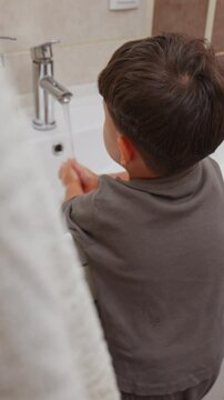 boy and baby child in bathroom,brushing teeth,washing hands with soap,combing hair.siblings,brothers in front of sink on tabouret chair.kids on toilet with lot of paper.