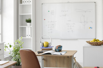 Apple with headphones and books on desk in classroom