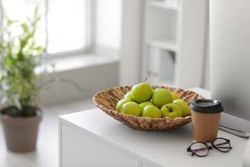 Apples with eyeglasses and coffee cup on teacher's desk in classroom, closeup