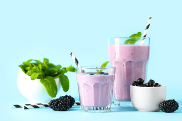 Glasses of fresh smoothie with black currant, blackberries and mint on blue background