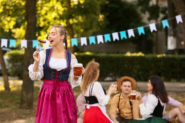 Happy Octoberfest waitress with beer and sausage outdoors