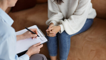 Unrecognizable Psychologist Talking With Female Client Taking Notes During Psychotherapy Session...