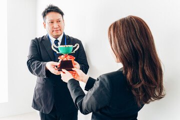 社内表彰で上司からトロフィーをもらうビジネスウーマン