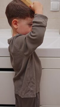 boy and baby child in bathroom,brushing teeth,washing hands with soap,combing hair.siblings,brothers in front of sink on tabouret chair.kids on toilet with lot of paper.