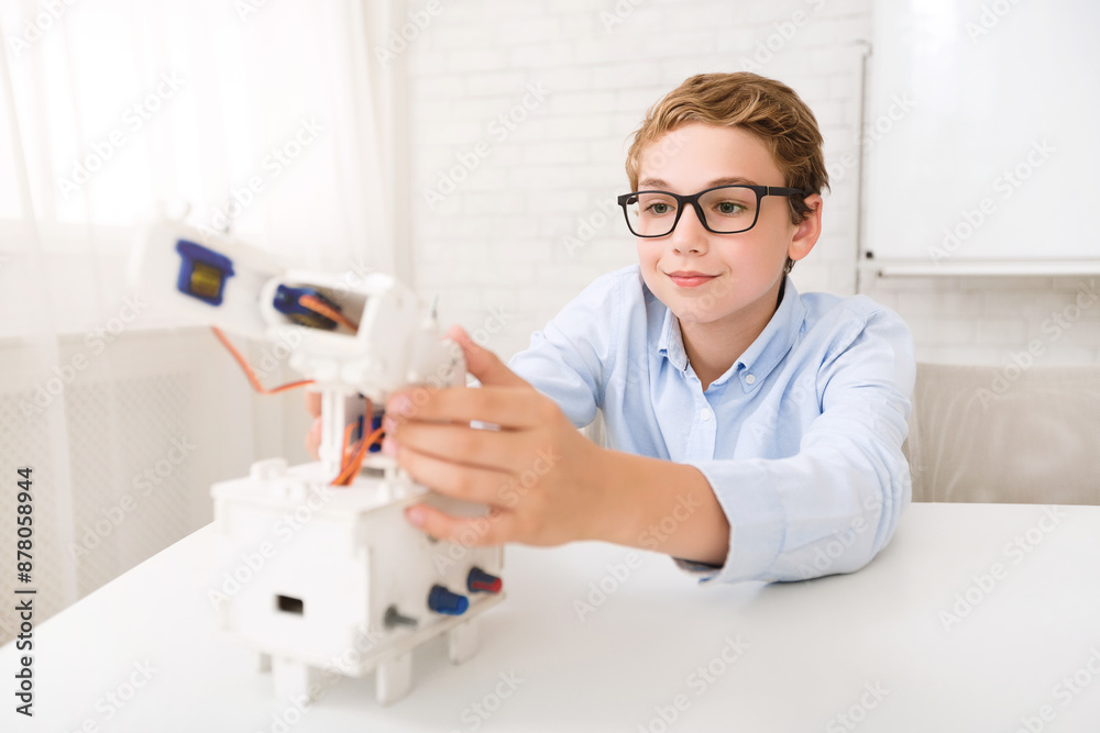 Poster a young boy sits at a desk in a classroom, focusing intently as he assembles a robotic arm kit. the 
