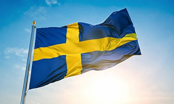 A blue and yellow flag with a cross on it. The flag is waving in the wind. The sky is clear and blue