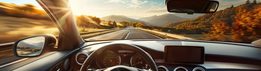 A focused driver is behind the wheel, with a view of the road and a beautiful landscape ahead, as seen through the windshield of the car on a sunny day.