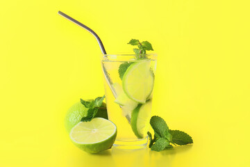 Glass of fresh lemonade with lime and mint on yellow background