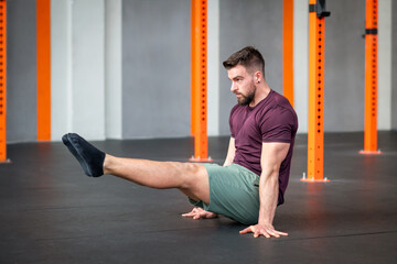 Fit sportsman doing calisthenics L sit position at gym