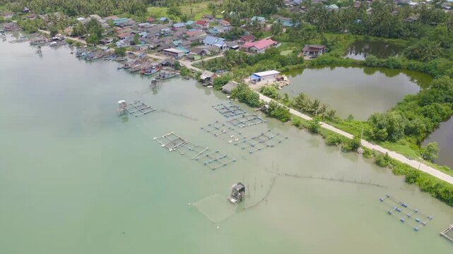 Aerial view of fishing trap net in canel with fisherman urban city village town houses, lake or river. Nature landscape fisheries and fishing tools at Pak Pha, Songkhla, Thailand. Aquaculture farming