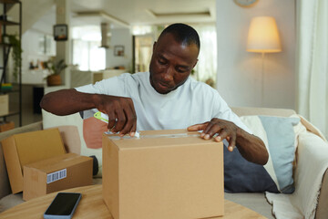 African American man unpacking his boxes in the room while ordering them online in marketplace