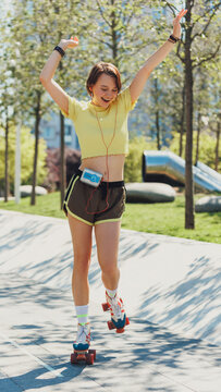 Skater girl training through city streets, wearing yellow crop top and brown shorts, and listening music on retro player. Concept of sport, active lifestyle, youth, summer holidays, hobby.