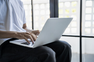The man is focused on his laptop screen typing work or a task at hand..
