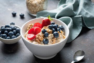 Breakfast oatmeal bowl with blueberries, strawberry and walnuts