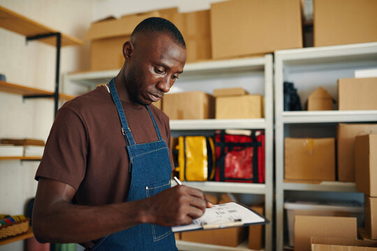 African American warehouse worker filling documents for shipping