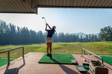 Young woman practices her golf swing on driving range Young girls practicing driving range.