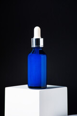 Blue glass cosmetic bottle, Skin care or sunscreen cosmetic with stylish props on black background.