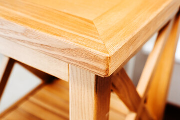 A close-up shot of a light brown wooden table top and leg with visible grain patterns