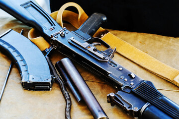 A close-up image of a disassembled military assault rifle with a magazine and sling