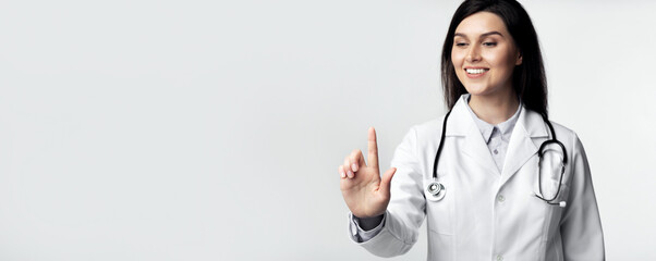 Female Doctor Pressing Invisible Button On Touchscreen Standing Over White Studio Background.
