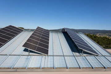 Fototapeta premium A set of solar panels are installed on a light blue metal roof, under a clear blue sky, symbolizing sustainable energy solutions with a modern, clean aesthetic touch.