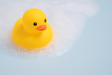 A yellow rubber duck is floating in a bathtub filled with bubbles