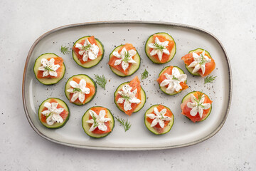 A white plate with cucumber slices and cream cheese on top