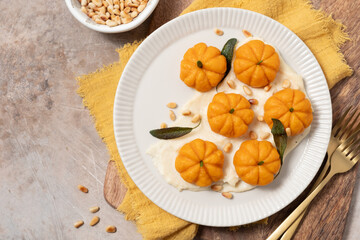 A plate of food with pumpkin shaped pastries and a bowl of nuts