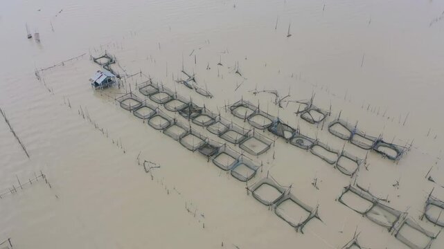 Aerial view of fishing trap net in canel with fisherman urban city village town houses, lake or river. Nature landscape fisheries and fishing tools at Pak Pha, Songkhla, Thailand. Aquaculture farming