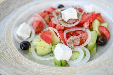 Fresh salad served in the restaurant. Shop salad in a plate. Tomato, onion, cucumber and cheese.