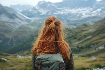 Naklejka premium Red-haired girl with a backpack against the backdrop of mountains. View from the back of a girl in the mountains