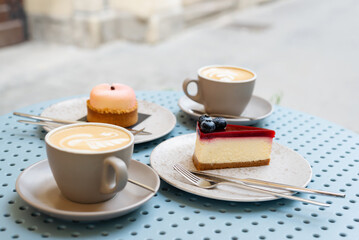 Two cups of cappuccino with desserts on the table in a sidewalk cafe.