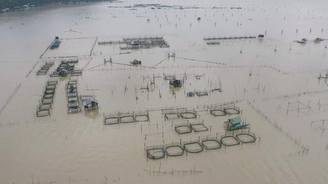 Aerial view of fishing trap net in canel with fisherman urban city village town houses, lake or river. Nature landscape fisheries and fishing tools at Pak Pha, Songkhla, Thailand. Aquaculture farming