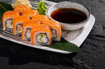 Fresh salmon sushi roll with soy sauce on dark slate