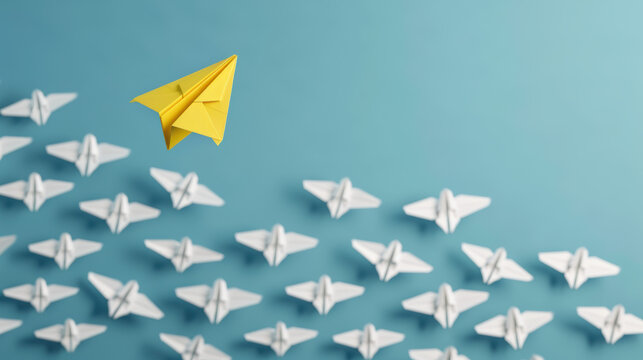 A yellow paper plane stands out while leading a group of white paper planes, symbolizing leadership, innovation, and uniqueness.