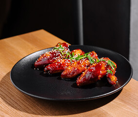 Sticky glazed chicken wings on black plate