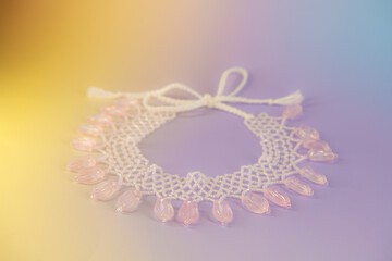 Light pink pendant ornate floral necklace made of beads on gradient background