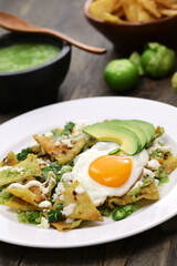 chilaquiles, Mexican breakfast. Totopos topped with salsa verde, fried egg, and avocado.